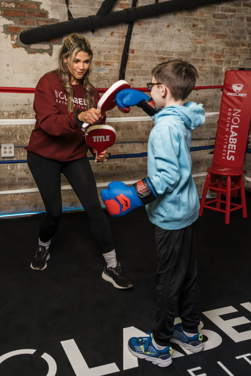 Mimi holding mitts for a young boxer in the ring