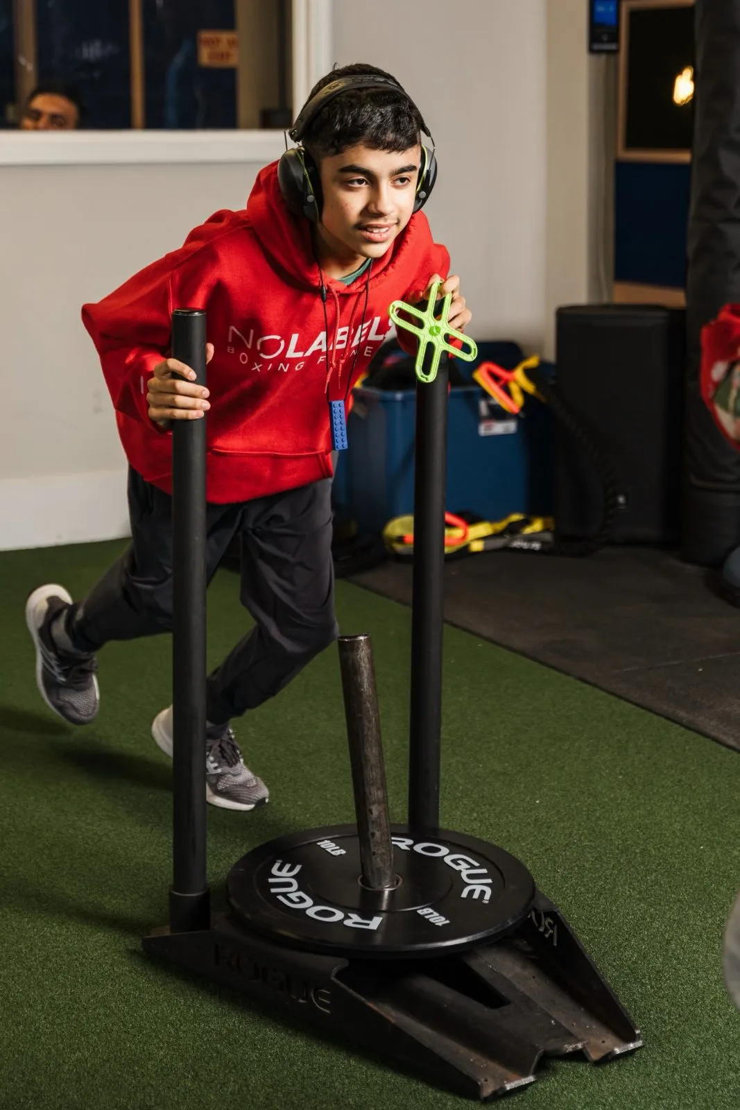 A young athlete wearing headphones pushing a weighted sled