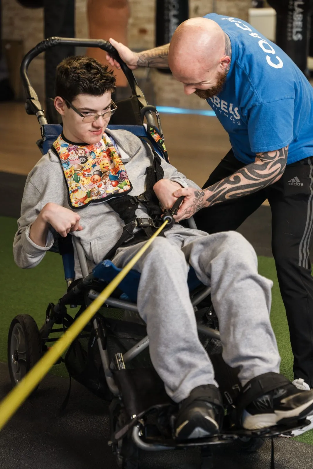 Coach Dave guiding an athlete in a wheelchair through a band exercise